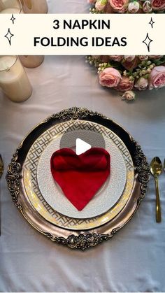 the table is set with plates, silverware and red heart shaped napkins on it