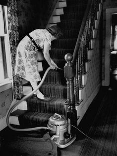 a woman is cleaning the stairs with a vacuum