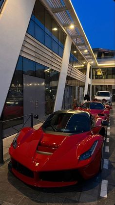 a row of red sports cars parked in front of a building