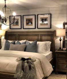 a bedroom with a bed, chandelier and pictures on the wall above it