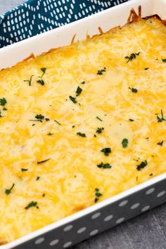 a casserole dish with cheese and parsley in it on a blue towel