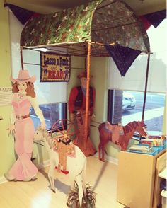 a fake horse is standing in front of a store window with an umbrella over it