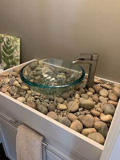 a glass bowl sink sitting on top of a rock covered counter next to a towel dispenser