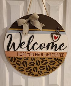 a welcome sign hanging on a door with coffee beans and a heart in the middle