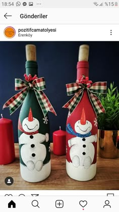 two decorated wine bottles sitting next to each other on top of a wooden table with candles