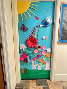 the door is decorated with paper flowers, butterflies and kites on blue wallpaper