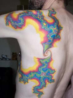 a man with his back turned to the camera, has colorful tattoos on his body