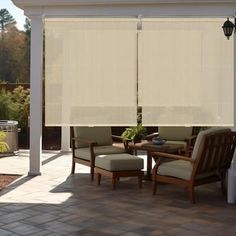 an outdoor patio with chairs, table and white blinds on the side of the house