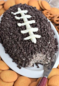 a football cake on a plate with cookies around it