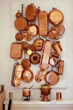 there are many copper pots and pans on the wall in this room, all together