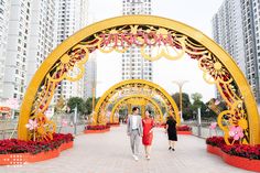 two people are walking under an archway decorated with flowers and gold decorations in the city