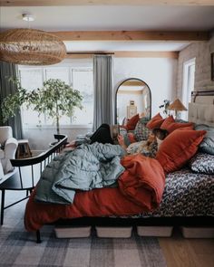 a woman laying on top of a bed in a bedroom next to a mirror and table