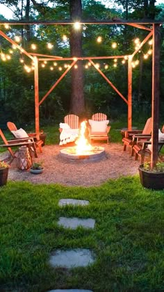 a fire pit surrounded by lawn chairs and string lights in the middle of a yard