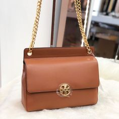 Tory Burch Shoilder Bag From The Chelsea Collection Crafted In Pebbled Leather With Gold-Tone Metal Hardware. This Shoulder Bag Features 1 Main Pocket, Zip Pocket, Flap With A Magnetic Snap Closure, And A Adjustable Leather/Chain Strap With A 19.92" Drop. Dimensions: H: 9.16" X L: 10.56". Timeless Cognac Bag With Branded Hardware, High-end Brown Shoulder Bag With Gold-tone Hardware, Gold Calf Leather Bag With Gold-tone Hardware, Timeless Gold Calf Leather Bag, Designer Soft Leather Shoulder Bag In Tan, Travel Bags In Gold Calf Leather, Gold Calf Leather Travel Bag, Classic Brown Flap Bag With Branded Hardware, Classic Cognac Shoulder Bag With Branded Hardware