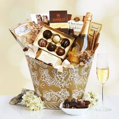 a basket filled with chocolates and champagne next to a glass of wine