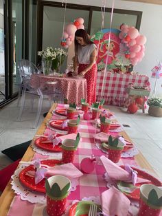 a table set up for a birthday party with pink and green plates, cups, and balloons