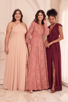 three women standing next to each other in long dresses and one is wearing a pink dress