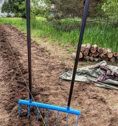 two poles are attached to the ground in front of some trees and dirt, with one pole sticking out from the ground