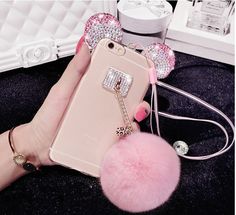 a woman's hand holding an iphone case with a pink pom - pom