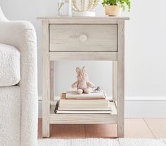 a small wooden table with a stuffed animal on top and books under the shelf next to it