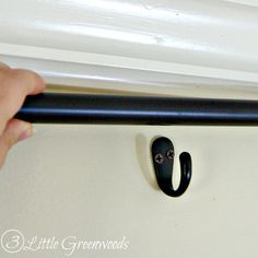 a hand is holding the handle to an open door with black handles and white trim