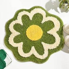 a green and white rug with a yellow flower on the center is next to slippers