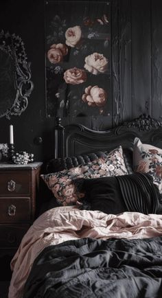 a bed with black sheets and pink flowers on the wall next to an old dresser