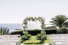 an outdoor ceremony setup with white flowers and greenery on the lawn by the ocean