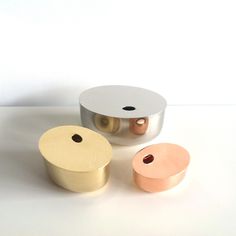 three metal objects sitting on top of a white table next to each other and one has a round object in the middle