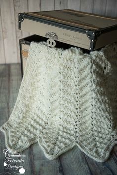 a white crocheted blanket sitting on top of an old suitcase