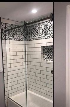 a bathroom with a glass shower door and tiled walls