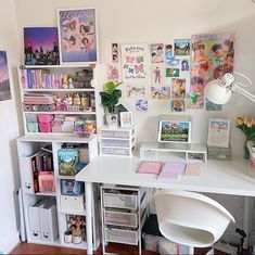 a white desk topped with lots of shelves filled with books and magazines next to a lamp