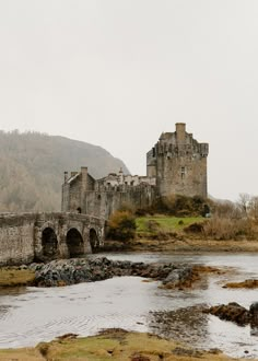 an old castle sitting on top of a hill next to a river