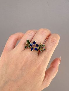 ♥ 14K Gold Vintage Ring with Three Blue Green Enamel Flowers with Ruby Center 7.11g R6734♥ The item measures 13.4mm in length (North South direction), 26mm in width (East West direction), and stands 7.3mm tall from the finger. Band width is 4mm. ♥ US size 8 (Free resizing up or down 1 size)♥ Material: 14K Gold ~ 7.11g♥ Gemstone: Ruby ♥ Note: This is a preowned piece that may have signs of wear and tear, and minor discoloration due to its age. This piece may or may not have been polished or sized Blue Enamel Ring In Fine Jewelry Style, Blue Enamel Ring Fine Jewelry, Blue Enamel Fine Jewelry Ring, Blue Hallmarked Enamel Ring, Blue Enamel Ring With Gemstone In Fine Jewelry Style, Blue Enamel Ring With Gemstone Fine Jewelry, Blue Enamel Ring With Gemstone, Fine Jewelry Enamel Multi-stone Ring Gift, Enamel Multi-stone Rings As A Gift