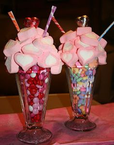 two vases filled with candy and marshmallows on top of a table