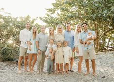 a family poses for a photo in front of some trees and bushes at the beach