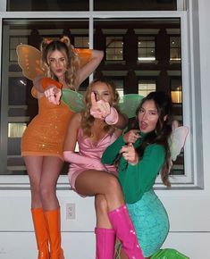 three beautiful women dressed in costumes posing for the camera with one pointing at the camera