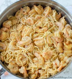 pasta with shrimp and parmesan cheese in a saucepan on a marble table