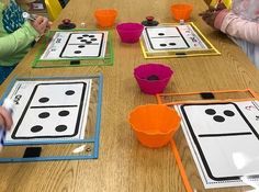 children are sitting at a table with matching numbers and shapes on them, making cards