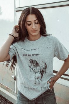 Introducing the Ride 'em Western Collection Graphic Tee - a must-have for any cowboy or cowgirl! Made with high-quality materials and featuring a stunning western design, this tee will keep you comfortable and stylish all day long. Perfect for casual outings or adding a touch of western flair to your wardrobe. 100% Cotton Casual T-shirt For Western-themed Fall Events, Fitted Crew Neck T-shirt For Rodeo, Western Style T-shirt For Ranch In Summer, Western Style Summer T-shirt, Fitted Graphic Print T-shirt For Ranch, Western Style Relaxed Fit Graphic T-shirt, Western Style Relaxed Fit T-shirt With Graphic Print, Western Style T-shirt For Spring Ranch, Graphic Print T-shirt For Rodeo