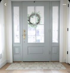 a door with a wreath hanging on it's side and two windows in the background