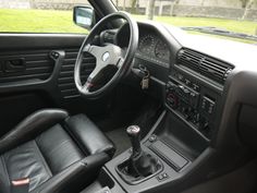 the interior of a car with black leather seats and dash board, steering wheel and dashboard controls