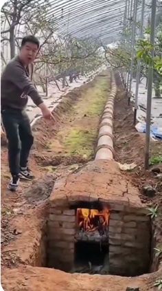 a man standing in front of a brick oven with flames coming out of the fire