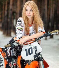 a woman sitting on top of an orange dirt bike