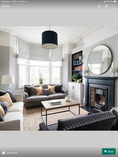 a living room filled with furniture and a fire place in front of a mirror on the wall