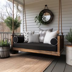 a porch swing with pillows and plants on it