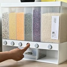 a person is pointing at some sort of cereal in a bin on the floor next to a couch