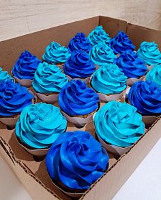 a box filled with blue cupcakes on top of a table