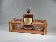 a bottle and glasses are sitting on a wooden tray with two empty shot glasses in front of it