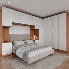 a bedroom with white walls and wooden flooring, built in cabinets and a large bed